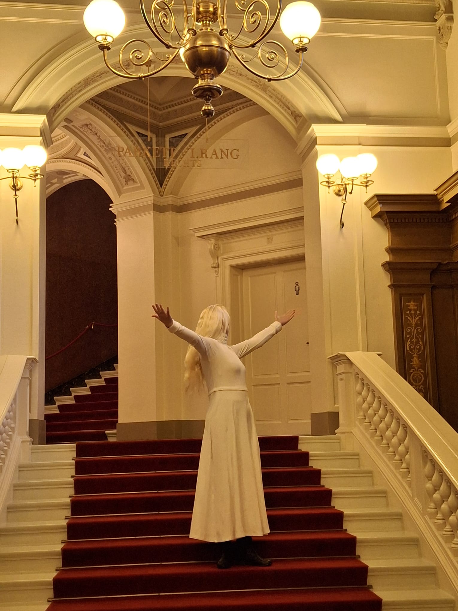 Annett Punte im weißen Kleid auf einer Treppe mit offenen Armen